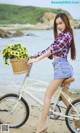 A woman riding a bike with a basket full of flowers.