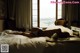 A woman laying on a bed in front of a window.